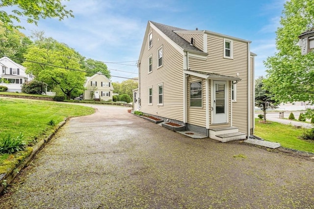 view of front facade featuring entry steps, driveway, and a front yard