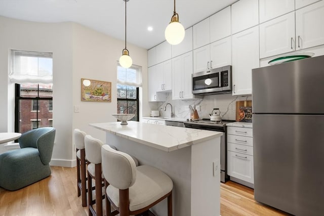 kitchen with stainless steel appliances, a kitchen island, light wood-style floors, white cabinets, and recessed lighting