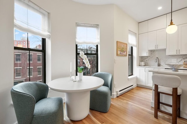 dining room featuring a baseboard radiator, light wood-style flooring, and healthy amount of natural light