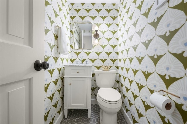 bathroom featuring wallpapered walls, toilet, vanity, and baseboards
