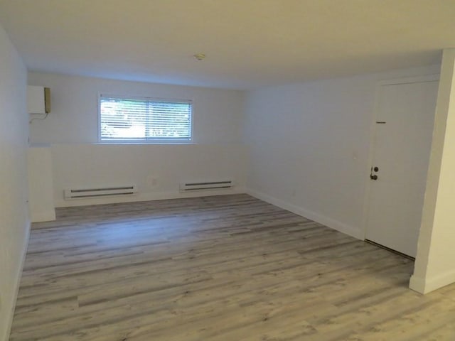 spare room with baseboard heating and light hardwood / wood-style flooring