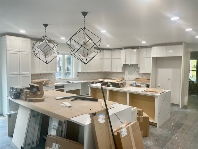 kitchen with tasteful backsplash, a center island, hanging light fixtures, dishwasher, and white cabinets