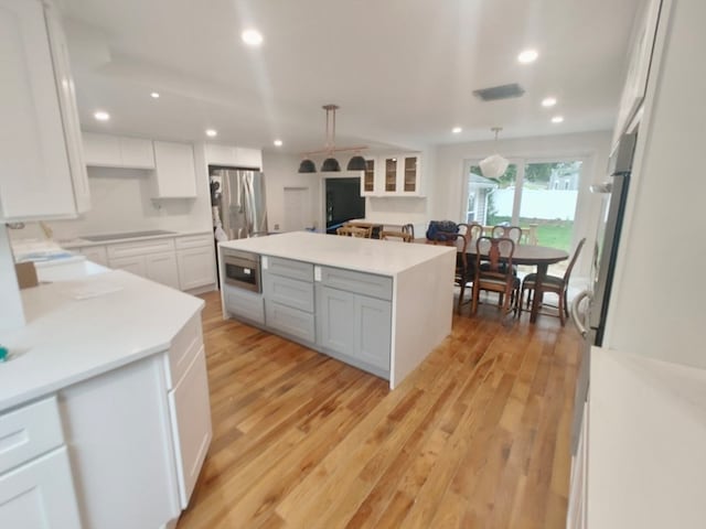 kitchen with white cabinetry, hanging light fixtures, appliances with stainless steel finishes, and a kitchen island