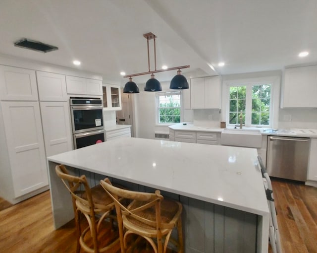 kitchen with white cabinetry, appliances with stainless steel finishes, a large island, and sink