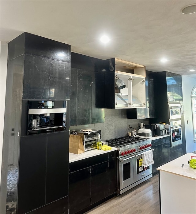 kitchen featuring backsplash, light hardwood / wood-style flooring, and appliances with stainless steel finishes