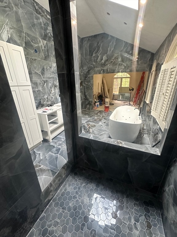 bathroom featuring vaulted ceiling and a tub to relax in