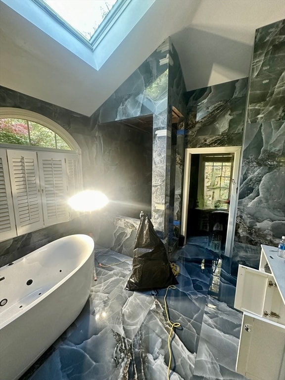 bathroom featuring a bathing tub and vaulted ceiling with skylight