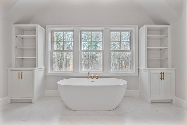 full bathroom featuring marble finish floor, a freestanding bath, a healthy amount of sunlight, and vaulted ceiling