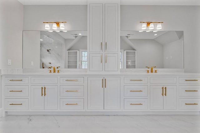 bathroom with a sink, double vanity, marble finish floor, and walk in shower