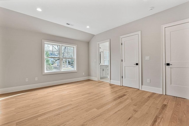 unfurnished bedroom with light wood finished floors, visible vents, connected bathroom, baseboards, and lofted ceiling