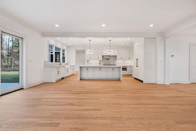 kitchen with light wood finished floors, ornamental molding, white cabinets, and light countertops