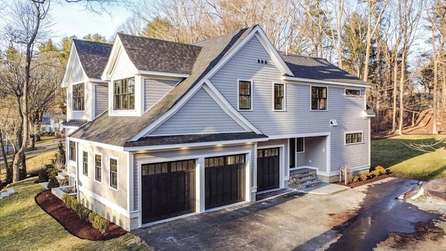 shingle-style home featuring a front yard, a garage, driveway, and a shingled roof