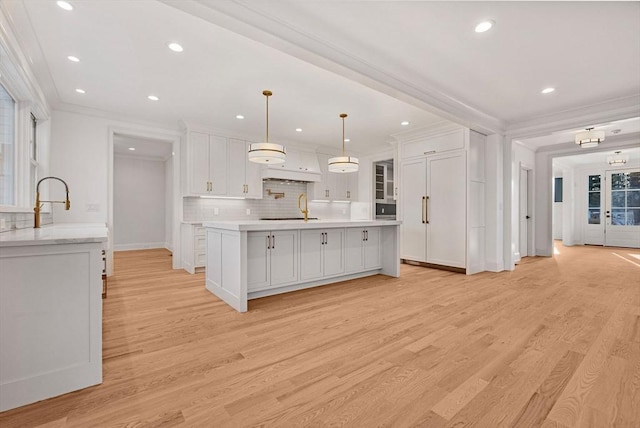 kitchen featuring light countertops, white cabinets, light wood-style flooring, and ornamental molding