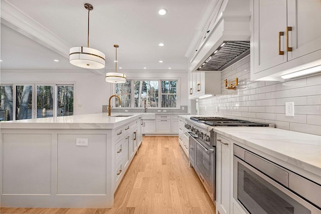 kitchen with a sink, stainless steel appliances, white cabinets, light stone countertops, and custom exhaust hood