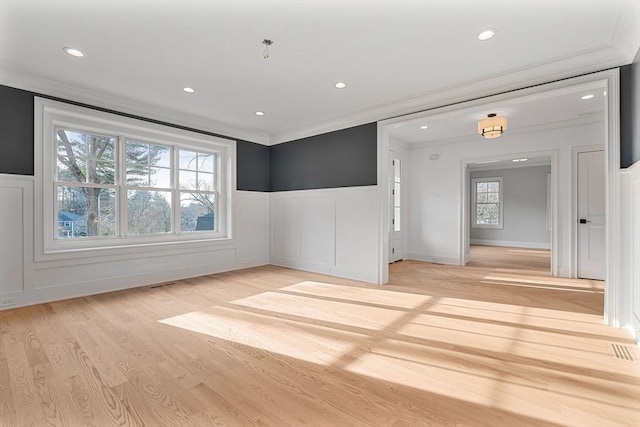 empty room featuring recessed lighting, a wainscoted wall, light wood-style floors, and ornamental molding