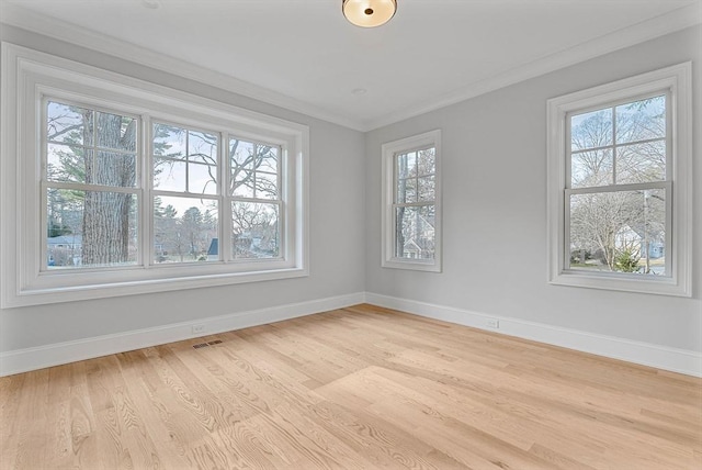 spare room featuring visible vents, light wood-style floors, baseboards, and ornamental molding