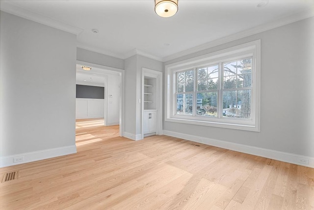 unfurnished room featuring built in features, light wood-style floors, baseboards, and ornamental molding