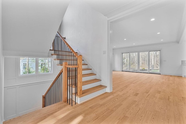 stairway featuring plenty of natural light, wood finished floors, recessed lighting, and ornamental molding