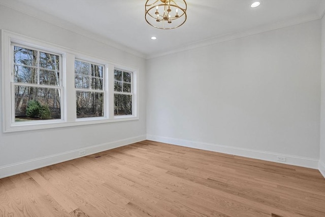 empty room with crown molding, baseboards, light wood finished floors, and a chandelier