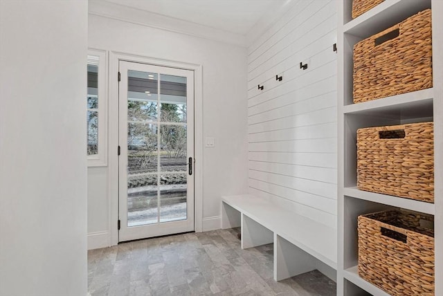 mudroom featuring light wood finished floors, wooden walls, and crown molding