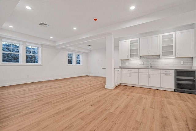 interior space featuring visible vents, light wood-style flooring, wine cooler, tasteful backsplash, and open floor plan