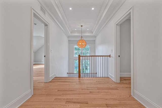 corridor featuring light wood-type flooring, an upstairs landing, visible vents, and ornamental molding