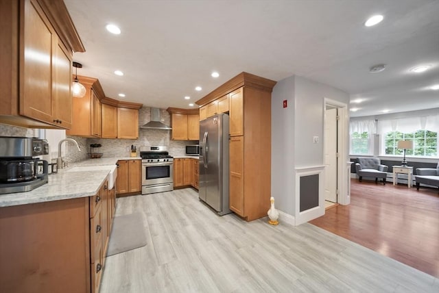 80 E St, Pepperell, MA 01463 - kitchen featuring stainless steel appliances, wall chimney range hood, light wood-type flooring, backsplash, and light stone countertops