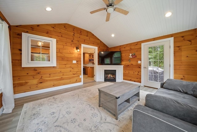 80 E St, Pepperell, MA 01463 - living area with lofted ceiling, light wood-type flooring, a warm lit fireplace, a ceiling fan, and wooden walls