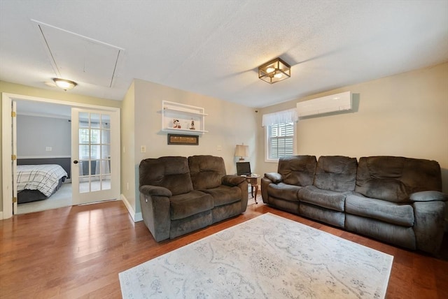 80 E St, Pepperell, MA 01463 - living room featuring attic access, a wall mounted air conditioner, and wood finished floors