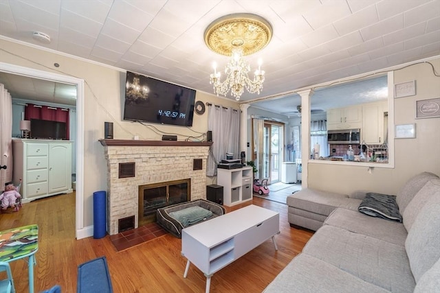 276 Oak St, Springfield, MA 01151 - living area with ornate columns, wood finished floors, a chandelier, a brick fireplace, and crown molding