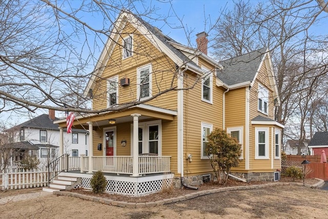 view of front of home with fence, covered porch, roof with shingles, and a chimney