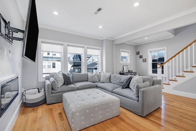 living area featuring light wood-type flooring, crown molding, baseboards, and stairs