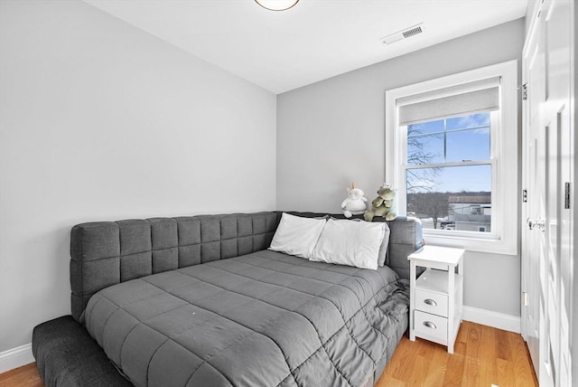 bedroom featuring light wood-type flooring, visible vents, and baseboards