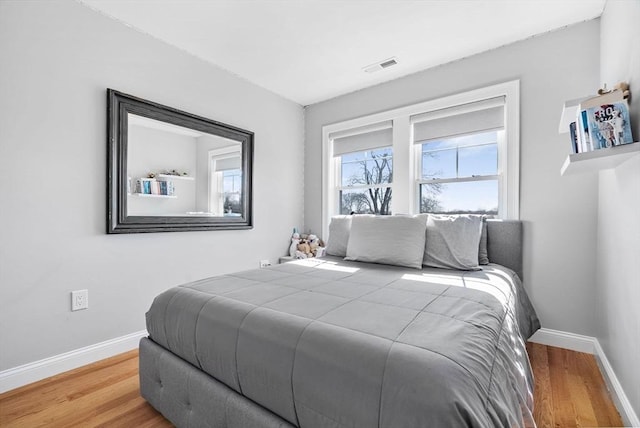 bedroom with visible vents, baseboards, and wood finished floors