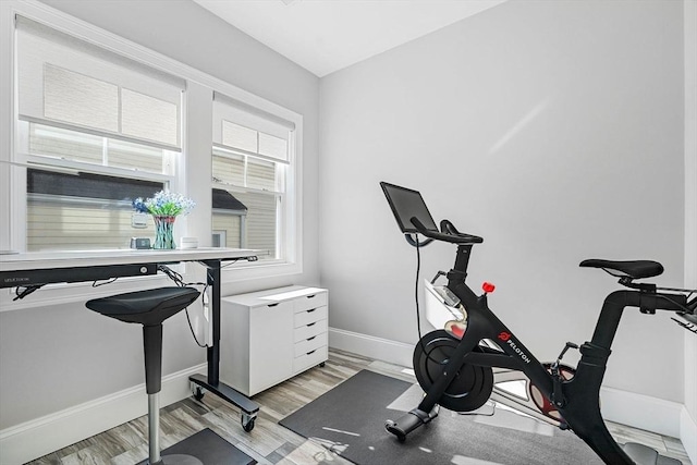 exercise room with light wood-type flooring and baseboards