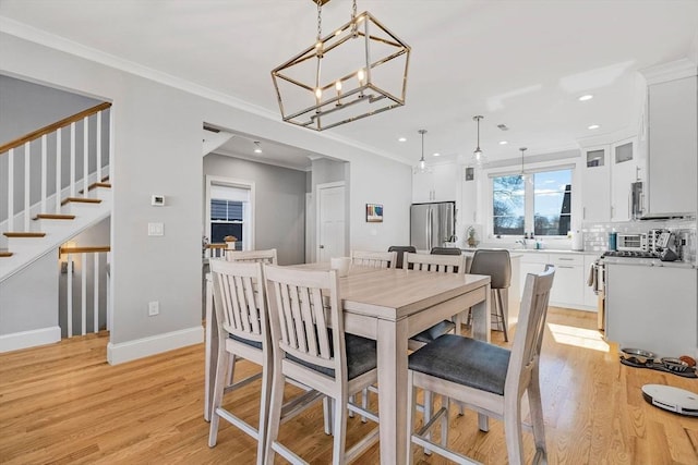 dining room featuring light wood-style floors, ornamental molding, stairway, and baseboards