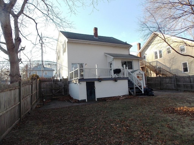 rear view of property with a wooden deck, stairway, a chimney, and a fenced backyard