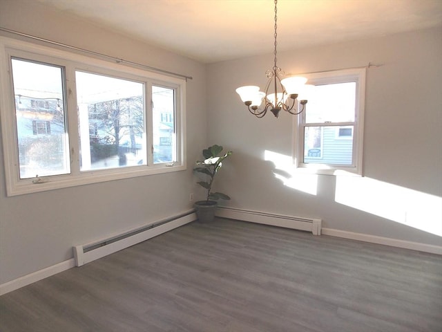 spare room with dark wood-type flooring, baseboard heating, and an inviting chandelier