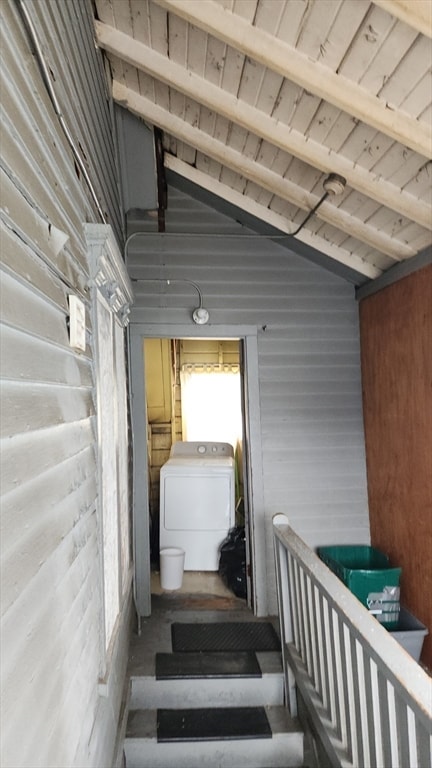 staircase featuring beamed ceiling, washer / clothes dryer, wooden ceiling, and wood walls