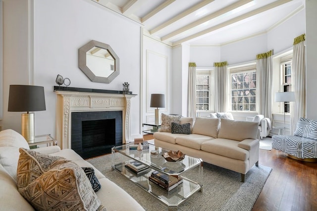 living room with dark hardwood / wood-style floors, beam ceiling, ornamental molding, and a fireplace