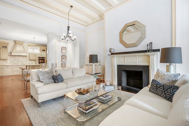 living room featuring hardwood / wood-style flooring, a notable chandelier, beam ceiling, and ornamental molding