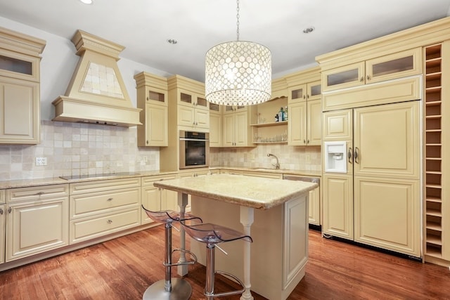 kitchen featuring appliances with stainless steel finishes, cream cabinets, pendant lighting, light hardwood / wood-style flooring, and a center island