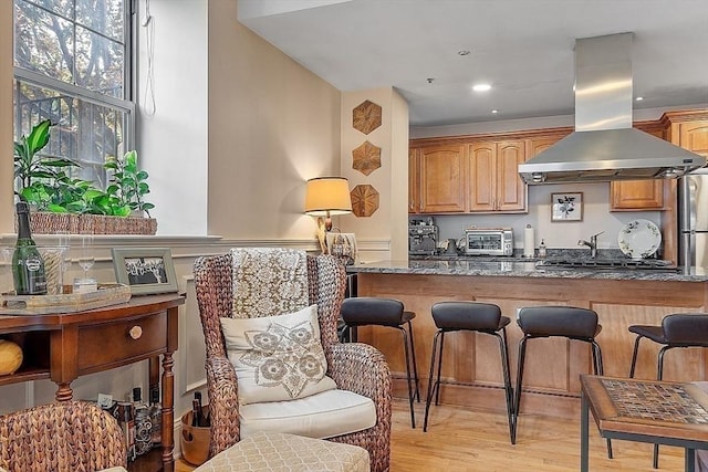 110 O St Unit 1, Boston, MA 02127 - kitchen with dark stone counters, island range hood, a breakfast bar, a toaster, and light wood finished floors