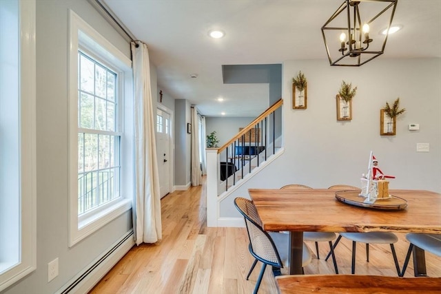 dining area with a notable chandelier, a baseboard heating unit, and light wood-type flooring