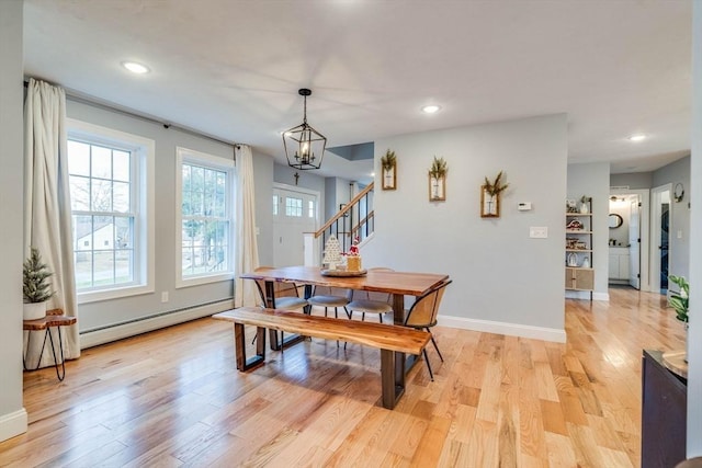 dining space with light hardwood / wood-style flooring, a baseboard radiator, and an inviting chandelier