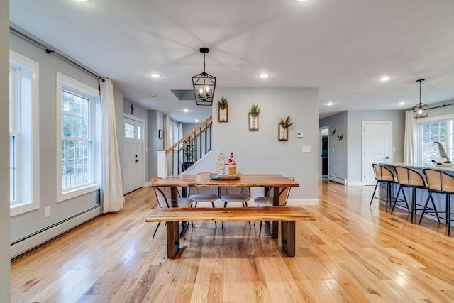 dining room featuring light hardwood / wood-style flooring, a baseboard heating unit, and a notable chandelier