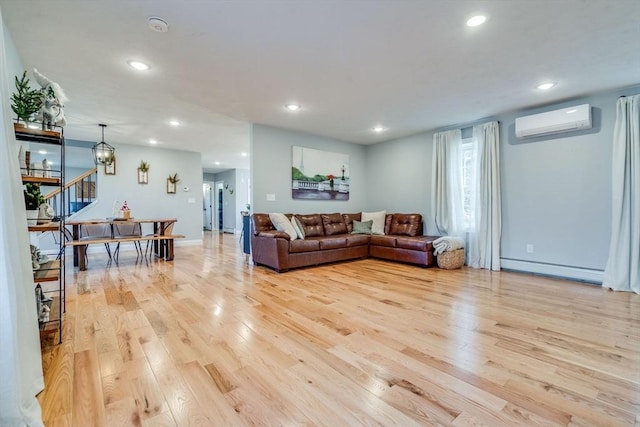 living room with a baseboard heating unit, a wall unit AC, and light hardwood / wood-style flooring