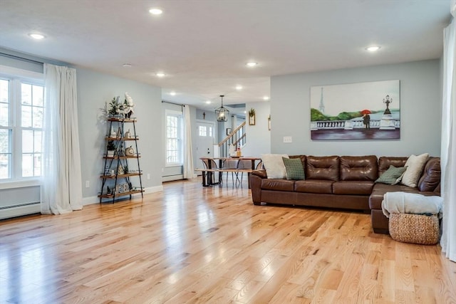 living room with light hardwood / wood-style floors, baseboard heating, and a healthy amount of sunlight