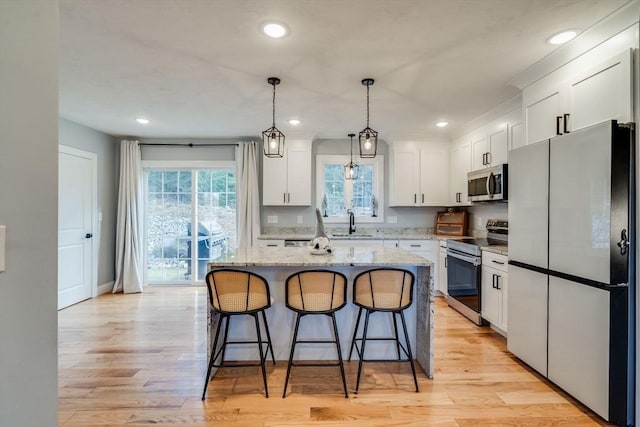 kitchen featuring white cabinets, a center island, light wood-type flooring, and appliances with stainless steel finishes