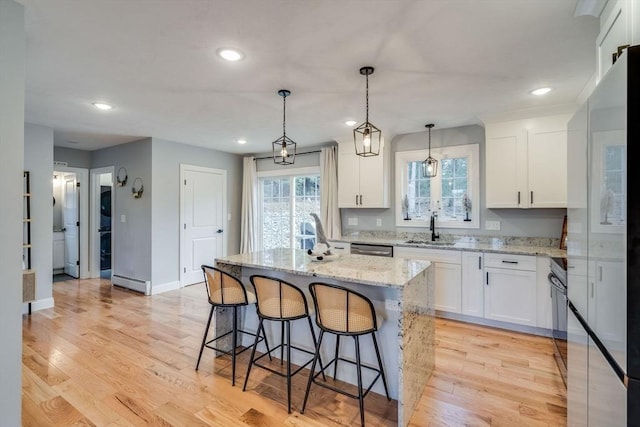 kitchen with sink, white cabinets, light wood-type flooring, and a kitchen island